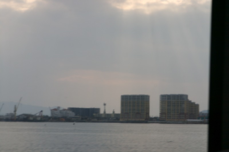 The sun poking through clouds onto the bay between the buildings and our boat.